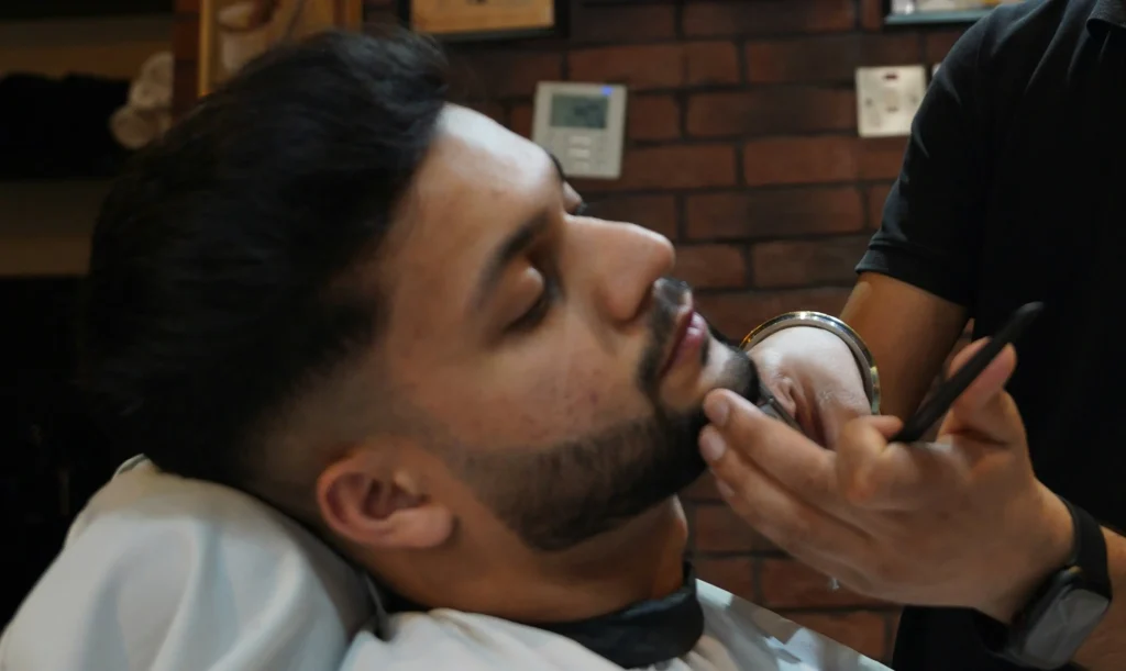 Barbero perfilando la barba de un cliente