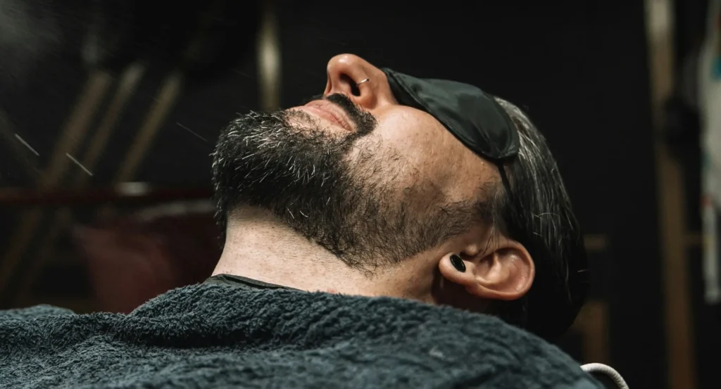 Barbero perfilando la barba de un cliente